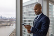 © ReeldealHD images - Businessman looking out of office in a skyscraper at the view holding a cell phone