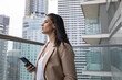 © ReeldealHD images - Businesswoman on office balcony using smartphone and looking at city skyline