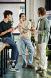 © LIGHTFIELD STUDIOS - young men in their 20s sharing ideas and holding coffee to go in modern office, startup team