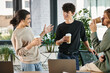 © LIGHTFIELD STUDIOS - friendly conversation between three young coworkers holding coffee to go in modern office, startup
