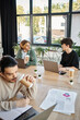 © LIGHTFIELD STUDIOS - Young professionals discussing ideas near laptops in a coworking space, blurred foreground