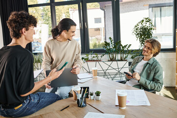 Wall Mural - Young startup team members brainstorming with gadgets in modern office space, men in their 20s