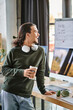 © LIGHTFIELD STUDIOS - Relaxed young man standing with stylus pen and coffee while laughing in post-production workspace