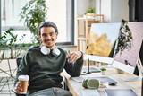 Fototapeta Panele - Relaxed young man with stylus pen and coffee smiling at a startup post-production workspace
