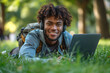 © Dzmitry - Smiling man wearing wireless headphones lying in grass with laptop in park