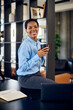 © bnenin - Portrait of a smiling African woman, posing for the camera with a cup of coffee, in her office.