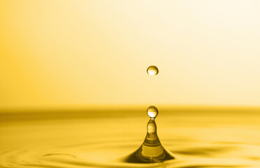 Wall Mural - Splash of golden oily liquid with drop on yellow background, closeup. Space for text