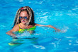 Pretty woman in a bright swimsuit and curly hair doing fitness in the  turquoise swimming pool waters in Jurmala, Latvia