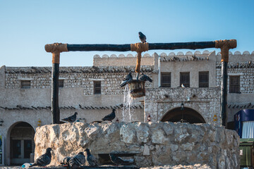 Doha, Qatar - February 8, 2024: The old well fountain and pigeons in front of Islamic Cultural Center Fanar, located in Souq Wakif, Doha, Qatar.