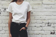 Modern Minimalism: Stylish White Tee and Black Jeans Against a Distressed White Brick Wall