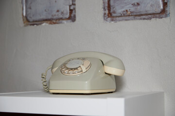 old telephone with a separate receiver and rotary dial on a board in front of two chimney flaps