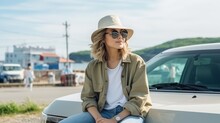 Young woman traveler wearing hat standing next to her car during a sunny summer holiday by the sea