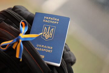 Ukrainian biometrical passport on black touristic backpack with ukrainian ribbon close up