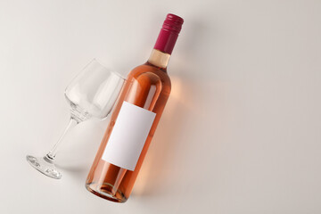 Sticker - Bottle of tasty rose wine and glass on white background, flat lay. Space for text