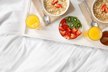 Wall Mural - Tasty breakfast served in bed. Oatmeal, juice, fruits and honey on tray, top view. Space for text