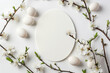 Minimalistic composition with easter eggs, a white oval plate, and blooming branches on a bright background