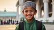 boy wearing Taqiyah with a blurry mosque in the background