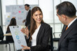 © Bavorndej - Businesswoman confidently discusses ESG (Environmental, Social, and Governance) criteria with a focused male colleague.
