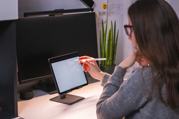 Young and confident women sitting on a modern home office taking notes on a tablet. 