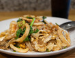 A delicious plate of stir-fried noodles with fresh seafood, vegetables, and a sprinkle of spices.
