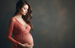Portrait of the young pregnant woman in red transparent peignoir. Image of pregnant woman touching her belly with hands. Pregnant middle aged mother portrait, caressing her belly.