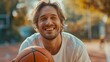 Happy beautiful man holds a basketball in his hands and laughs while looking at the camera