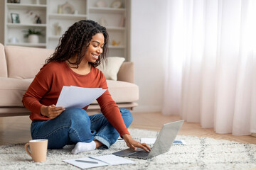 Wall Mural - Smiling Black Freelancer Woman Working With Laptop And Papers At Home