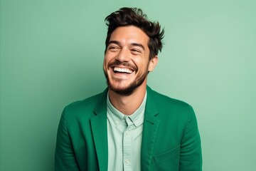 Wall Mural - Portrait of a happy young man laughing and looking at camera over green background