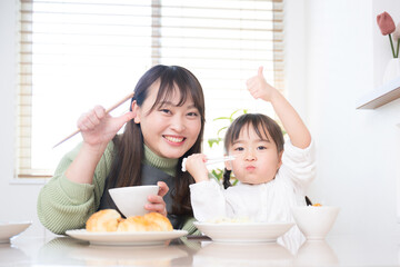 メインビジュアルにも！一緒のご飯は美味しいね！の表情をする母と娘の親子　いただきます