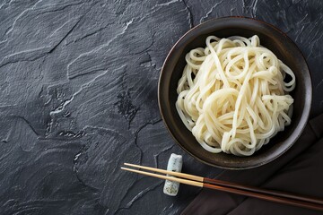 Canvas Print - Top view of udon noodles a traditional Japanese dish served in a bowl on a black slate table