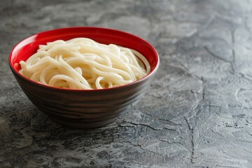 Canvas Print - Udon noodles in red bowl on stone table in Japan