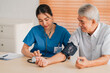 Medical health insurance service, Asian caregiver doctor examine older patient use blood pressure gauge. Young woman therapist nurse nursing home taking care to senior elderly man