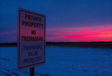 Sign "No Trespassing" In The Agricultural Field In Sunset Light In Winter.
