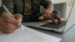 © Yuliia - Close up view unrecognizable man male guy working laptop from home browsing internet cropped shot businessman typing computer write notes writing legal document business paperwork pay bills loan taxes