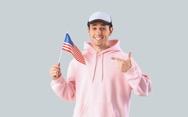 Wall Mural - Young man pointing at USA flag on light background