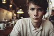 Boy with brown hair, blue eyes and freckles with melancholic look at a café
