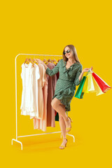 Sticker - Pretty young woman with shopping bags choosing dress on orange background