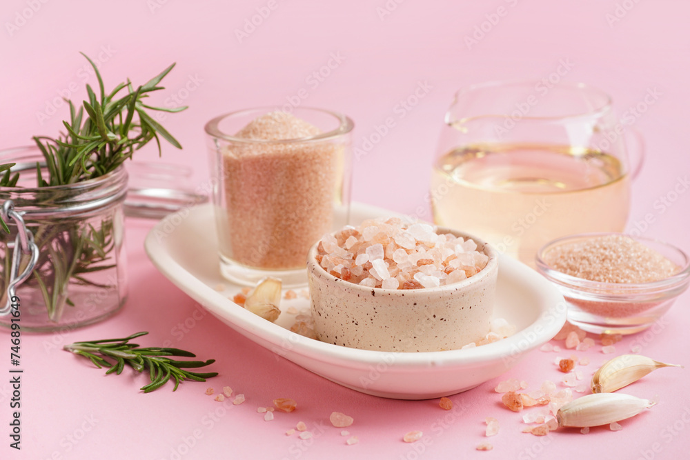 Bowls with Himalayan pink salt and garlic on pink background