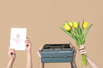 Wall Mural - Hands holding vintage typewriter, tulips and festive postcard with text HAPPY WOMEN'S DAY on beige background