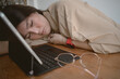 © Sevendeman - Asian Thai woman taking a nap, fall asleep, resting her head on arm while working and using laptop on wooden table, tired of work sitting on chair.