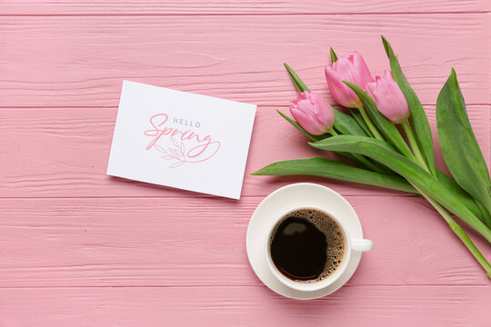 Greeting card with text HELLO SPRING, beautiful tulips and cup of coffee on pink wooden background