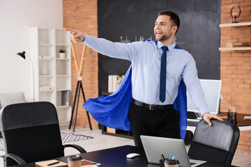 Poster - Businessman with superhero cape pointing at something in office