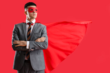 Wall Mural - Businessman dressed as superhero on red background