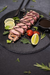 Wall Mural - sliced grilled cooked piece of tuna fillet on black stone serving board