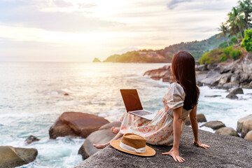 Young woman freelancer traveler working online using laptop while traveling on summer vacation, Freelance and workation concept