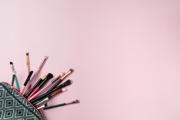 Canvas Print - Makeup brushes falling out of cosmetics on pink background