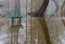 Spring Flooding In The Park. Bench, Sidewalk And Trees In The Water.