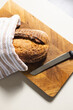 A loaf of bread and a knife rest on a wooden cutting board, partially covered by a striped towel