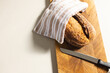 A freshly baked loaf of bread rests on a wooden cutting board beside a knife, with copy space