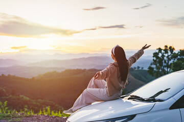 Young woman traveler sitting with car watching a beautiful sunrise over the mountain while traveling road trip on vacation, Travel concept